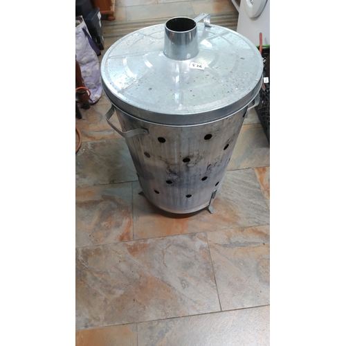 526 - Galvanised metal incinerator bin with domed lid and central flue, the cylindrical body pierced with ... 