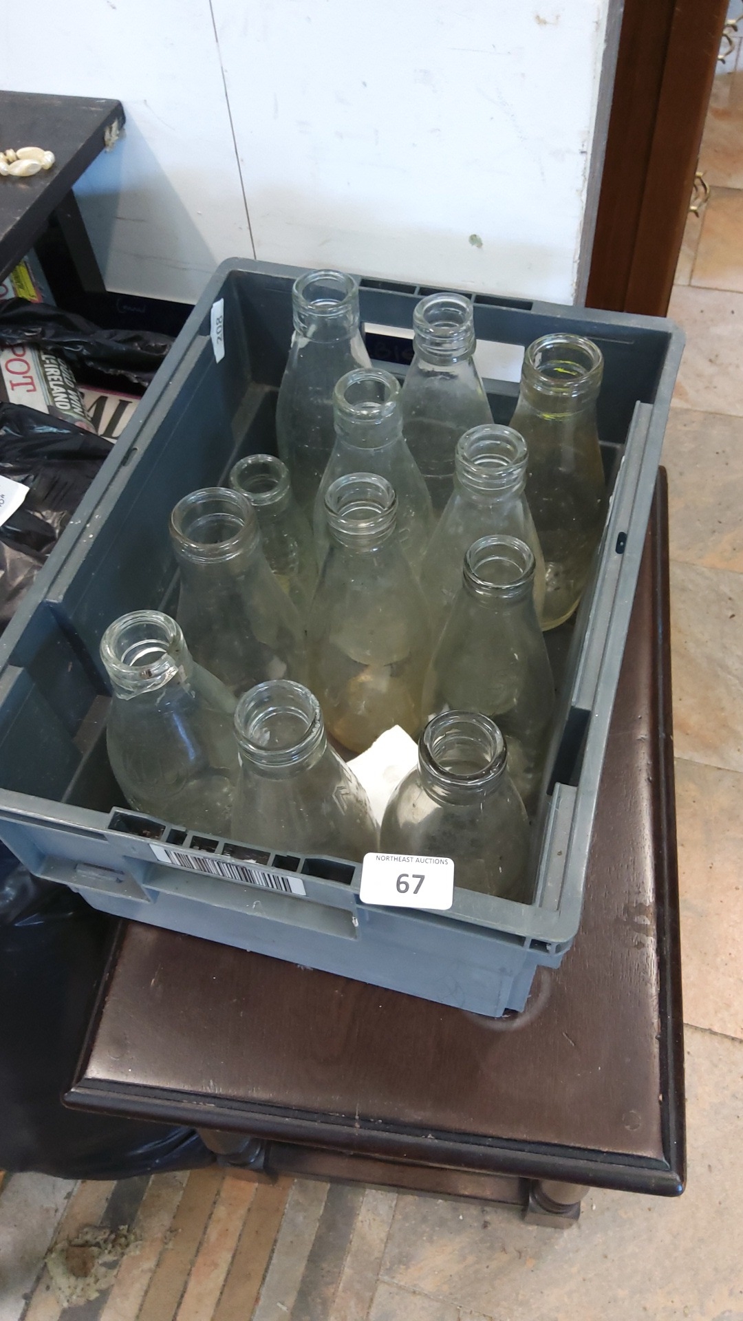 A quantity of clear glass milk bottles of tapering form, some with ...