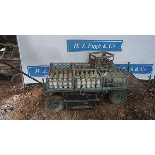 418 - Milk bottles and crates on electric trolley. Charger in shed office