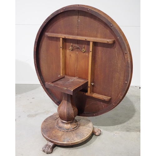 2 - Mahogany circular tilt top dining table on a pedestal base with lion pad feet and castors