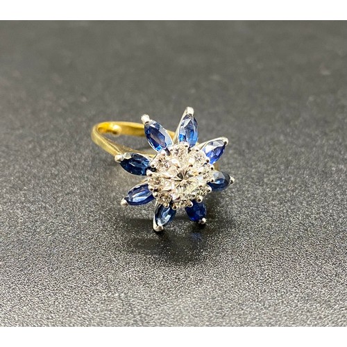 200B - A yellow gold sapphire and diamond cluster ring. Claw set central round brilliant-cut within a borde... 