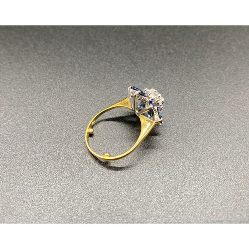 200B - A yellow gold sapphire and diamond cluster ring. Claw set central round brilliant-cut within a borde... 