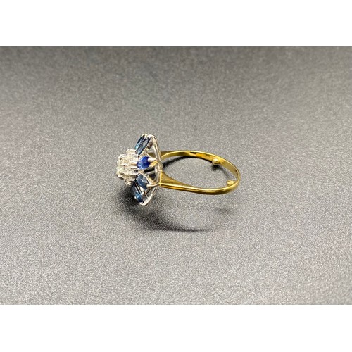 200B - A yellow gold sapphire and diamond cluster ring. Claw set central round brilliant-cut within a borde... 