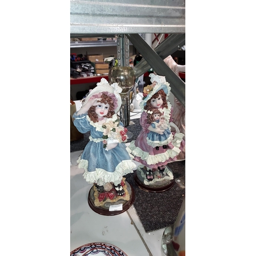 563 - 2 Vintage Girl Ornaments, 1 Holding Flower, 1 Holding Doll. Both On Wooden Plinths