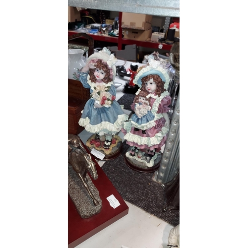 550 - 2 Vintage Girl Ornaments, 1 Holding Flower, 1 Holding Doll. Both On Wooden Plinths