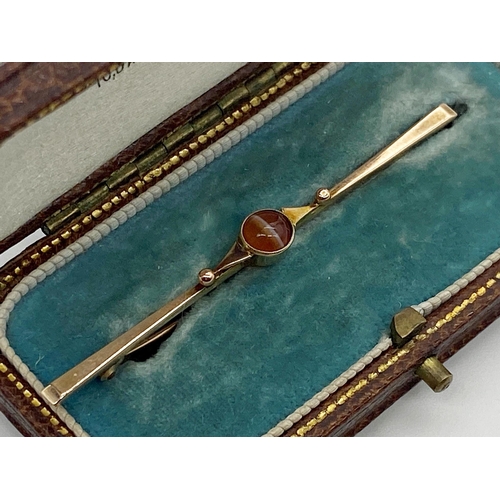 306 - A 9ct gold bar brooch with a central cabochon banded agate in fitted box 5 cm long approx together w... 