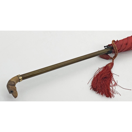 138 - Early 20th century red parasol, with finely carved horn dog head knop, 72cm long