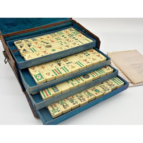 97 - Antique Mah Jong set, in leather case enclosing five tiers on polychrome bone tiles, with four games... 