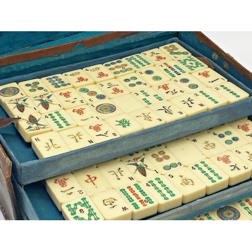 97 - Antique Mah Jong set, in leather case enclosing five tiers on polychrome bone tiles, with four games... 