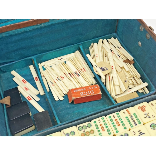 97 - Antique Mah Jong set, in leather case enclosing five tiers on polychrome bone tiles, with four games... 