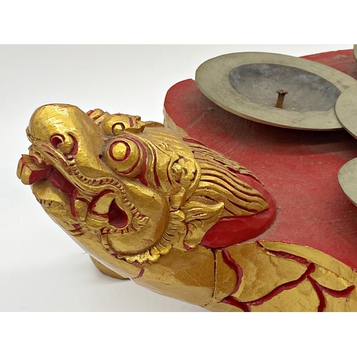 102 - Carved Chinese Ceng Ceng (turtle cymbals) gilt highlights on a red ground, 48cm long