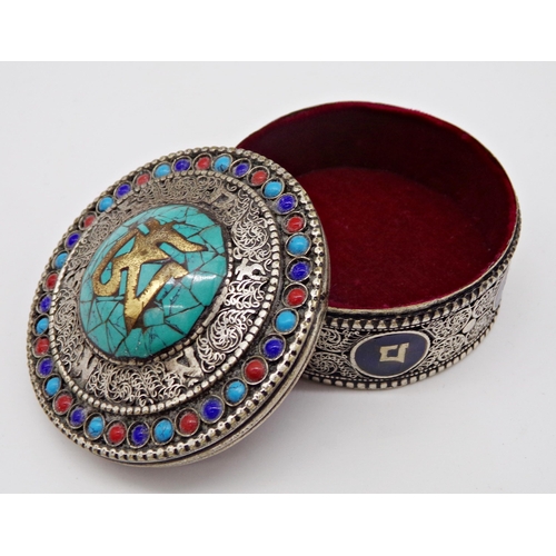 228 - Eastern filigree silver box, the top inlaid with turquoise, over a base with enamel panels, 6cm diam... 