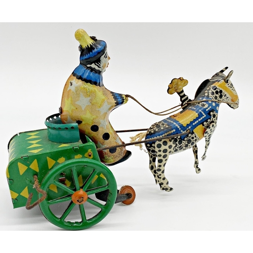 180 - German tinplate windup toy of a clown on a horse drawn cart 19cm long