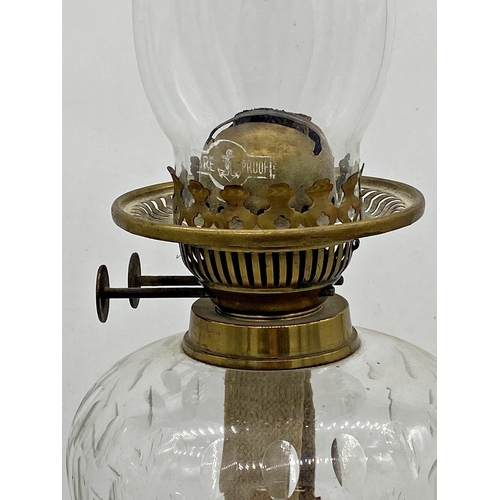 1057 - An old brass Corinthian column oil lamp with geometric cut glass reservoir, 74cm including flue