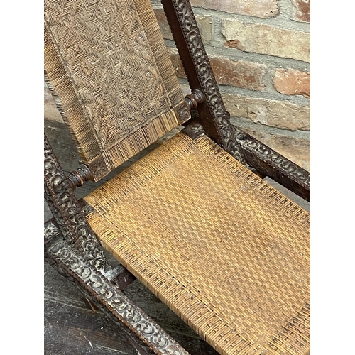 1151 - A North-Indian folding campaign type lounge chair with woven back and seat mounted by opposing eleph... 