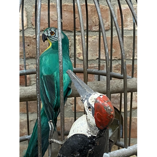 439 - Exceptional cast copper wirework bird cage with simulated woodpeckers and feather parrot, 100cm high