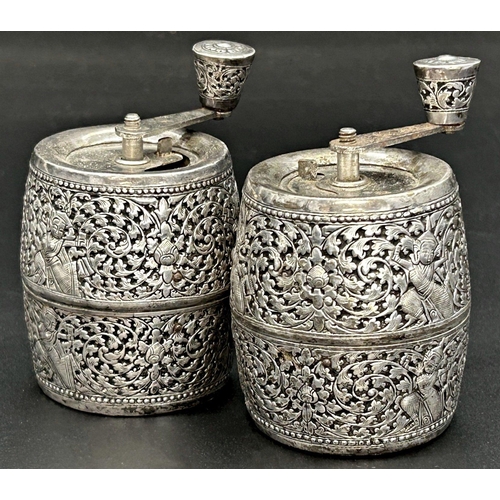 87 - Pair of eastern white metal pepper grinders, embossed and pierced with figures amidst scrolled folia... 