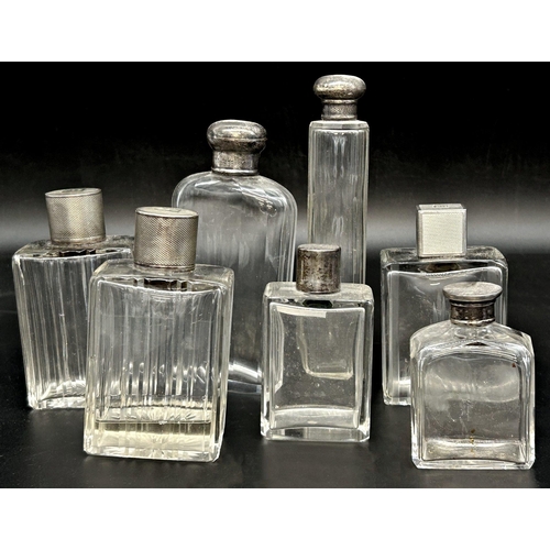 119 - Seven silver topped glass dressing bottles (7)