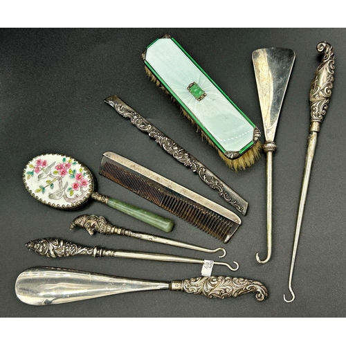 106 - Mixed collection of dressing silver comprising three lace hooks, two shoehorns, 2 comb tops, enamel ... 