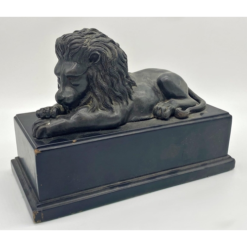 1184 - Cast metal probably bronze statue of a recumbent lion upon a stepped square ebonised wooden plinth b... 