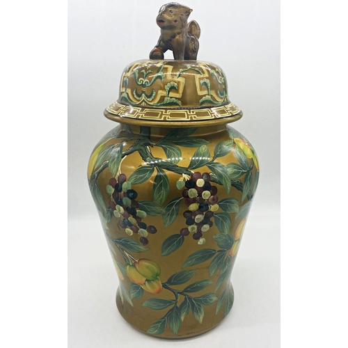 1075 - A large Chinese lidded ginger jar mounted by a Dog of Fo with painted decoration of fruit amidst bra... 