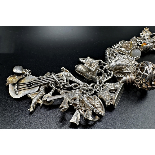 288 - Silver charm bracelet fitted with 26 charms, 84.8g