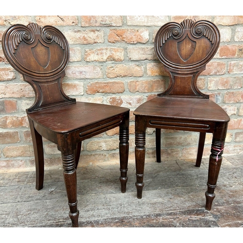 1439 - A pair of Regency plum pudding mahogany hall chairs with shell and scrolled carved backs on turned f... 