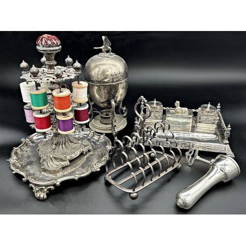 205 - Mixed quantity of silver plate comprising - desk standish with Egyptian motifs, cotton reel display ... 