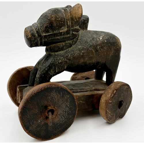 546 - Carved Indian folk art treen Nandi bull on wheels, traces of original paint, 21cm long