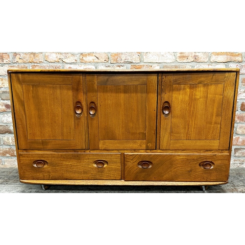 1202 - Ercol light elm sideboard, three cupboard doors over two drawers on casters, 76cm high x 130cm wide