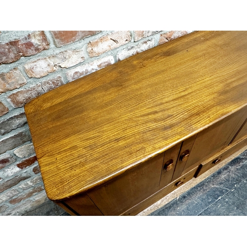 1202 - Ercol light elm sideboard, three cupboard doors over two drawers on casters, 76cm high x 130cm wide