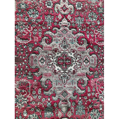 1410 - Heriz carpet, with medallion and scrolled decoration on a red ground, 310 x 200cm