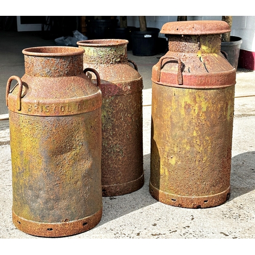 1056 - Three antique steel milk churns, one inscribed Bristol Dairy, Height 75cm x 35cm Diameter