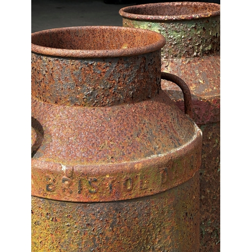 1056 - Three antique steel milk churns, one inscribed Bristol Dairy, Height 75cm x 35cm Diameter