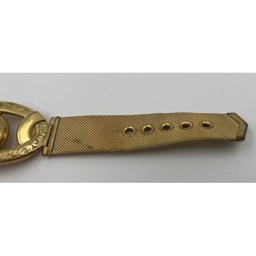 318 - Yellow metal stylised bracelet, with twin pierced scrolled hinged centre, on a watch type strap, mar... 