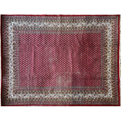 1454 - Large Persian wool full pile carpet with geometric paisley design upon a red ground, 340cm x 240cm.