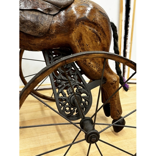 1281 - Carved horse tricycle, with good patina leather saddle and iron wheels and framework, 88cm high.