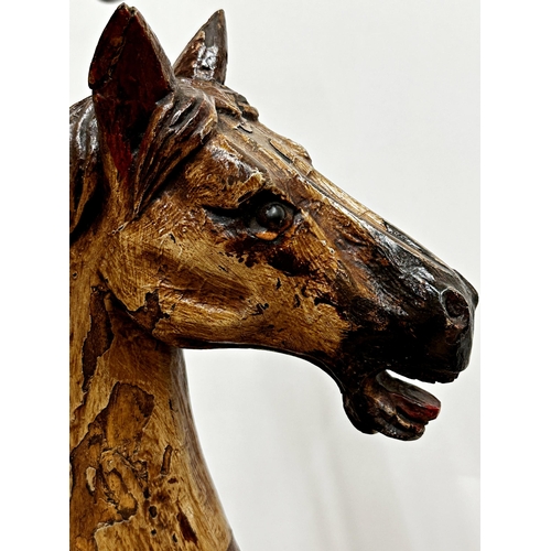 1281 - Carved horse tricycle, with good patina leather saddle and iron wheels and framework, 88cm high.