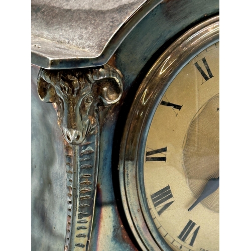 42 - Silver plated Kendall & Dent of London mantel clock in the Adam style with rams head and hoof feet, ... 