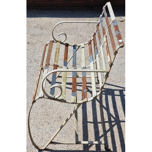 1043 - A weathered sprung steel garden bench with strapwork seat and scrolled detail, 78 x 120cm