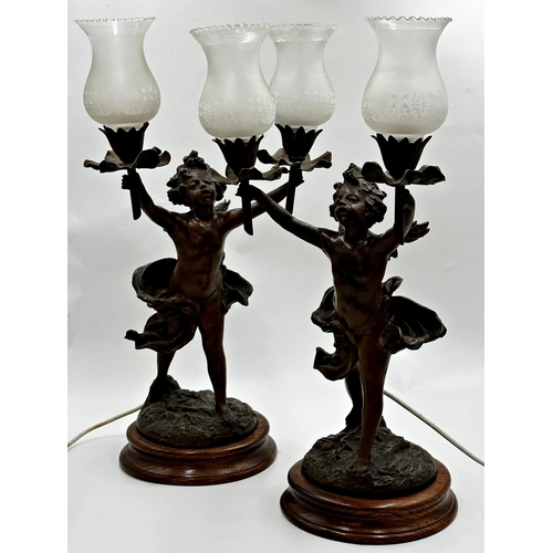 1163 - A pair of French figural spelter twin branch table lamps in the form of cherubs, the sconces are bei... 