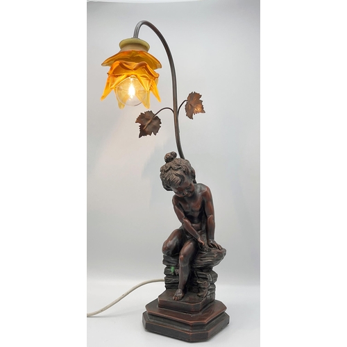 107 - Bronzed resin figural table lamp with a seated cherub and floral glass shade, 59cm high