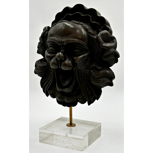 518 - Eastern bronzed resin mask of a mythical beast raised on a leucite plinth base, 30cm high