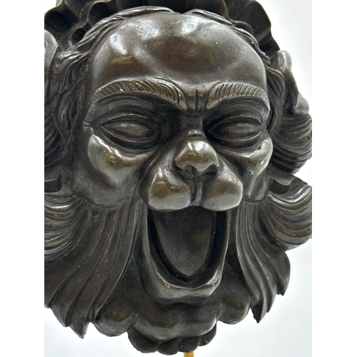 518 - Eastern bronzed resin mask of a mythical beast raised on a leucite plinth base, 30cm high