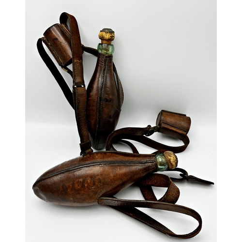 717 - Pair of antique leather applied riding flasks fitted with a glass bottle with original cork, upon le... 