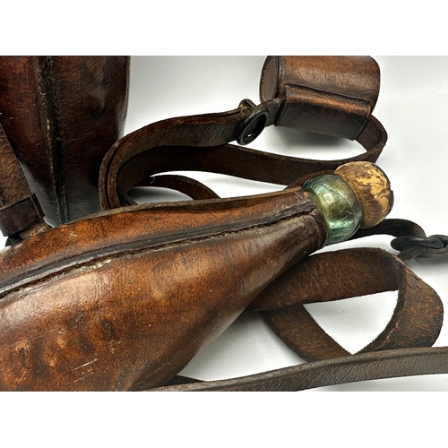 717 - Pair of antique leather applied riding flasks fitted with a glass bottle with original cork, upon le... 