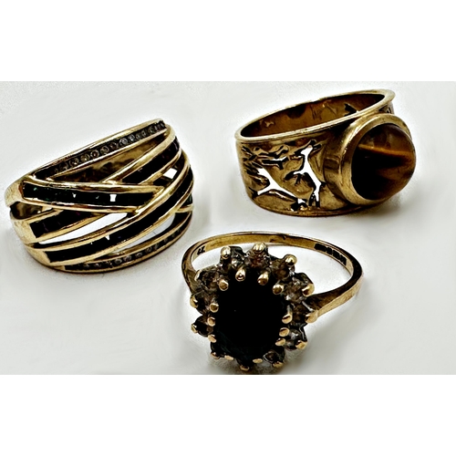 125 - Three fancy 9ct rings - Tiger's eye cabochon ring, size O, multi gem crossover ring, size O and garn... 