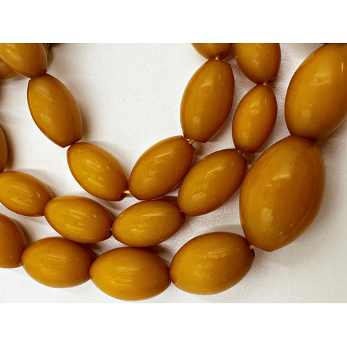 128 - String of graduated amber or amber coloured beads, 88cm long, 95.1g gross