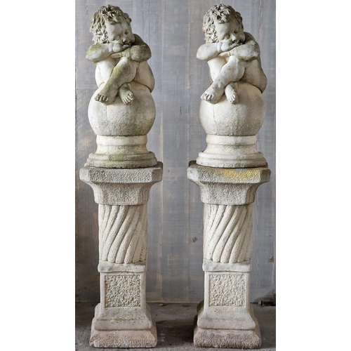 1041 - Pair of reconstituted stone cherub figures seated upon sphere cap finials, raised on column pedestal... 