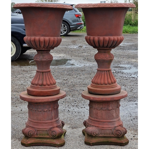 1062 - Pair of reconstituted stone garden urns with lobed bowls and flared rims, raised on Corinthian colum... 